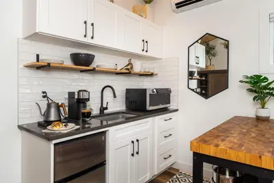 a kitchen with white cabinets and a sink at Coastal Creative Garden Studio in Colwood