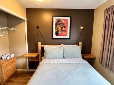 a bedroom with a bed and a painting on the wall at Mountain View 3br Loft Walk To Dt king fireplace in Canmore
