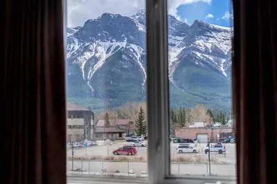 a view of a snowy mountain from a window at Mountain View 3br Loft Walk To Dt king fireplace in Canmore
