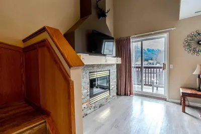 a living room with a fireplace and a balcony at Mountain View 3br Loft Walk To Dt king fireplace in Canmore