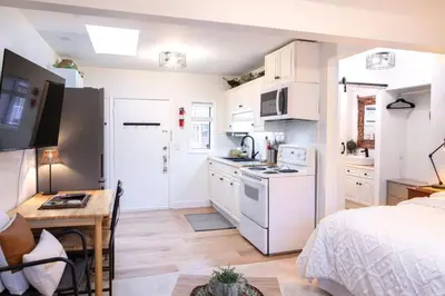 a kitchen with white appliances and a bed in a room at The Nook, Top Floor Suite with Lake and Mtn View in Harrison Hot Springs