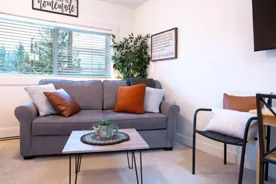 a living room with a couch and a table at The Nook, Top Floor Suite with Lake and Mtn View in Harrison Hot Springs