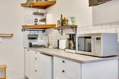 a kitchen with white cabinets and silver appliances at Grey Whale, Pet Friendly Studio at The Beach in Ucluelet
