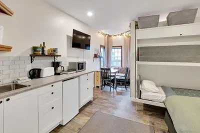 a bedroom with a bunk bed and a kitchen at Grey Whale, Pet Friendly Studio at The Beach in Ucluelet