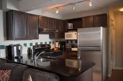 a kitchen with wooden cabinets and a stainless steel refrigerator at Moguls, Lofted Ski in Ski Out with Hot Tub Access in Panorama
