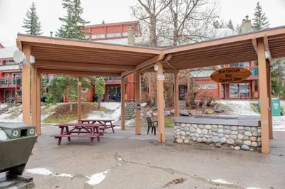a wooden pavilion with picnic tables and a grill at Moguls, Lofted Ski in Ski Out with Hot Tub Access in Panorama