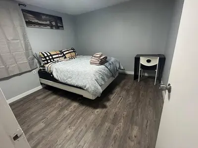 a bedroom with a bed and a wooden floor at Cute Highlandpark (Lower B Unit) in Calgary