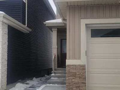 a house with a garage door and snow on the sidewalk at Cozy Basement Suite - private entrance - Free Netflix in Edmonton