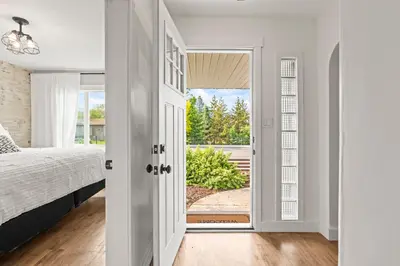 a bedroom with a bed and a door leading to a porch at Stunning Heritage Home, Sleep 8, Hot Tub, Private Yard, Firepit in Vernon
