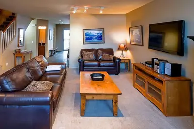 a living room with leather couches and a tv at Thunder Ridge Chalet by Fernie Lodging Company in Fernie