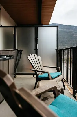 a pair of chairs on a balcony with a view at Revelstoke Alpine Retreat - RARE One-Bedroom Condo in Revelstoke