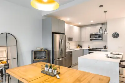 a kitchen with a wooden table and a stainless steel refrigerator at Revelstoke Alpine Retreat - RARE One-Bedroom Condo in Revelstoke