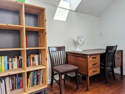 a desk with two chairs next to a book shelf at Ocean Park Loft in Surrey