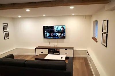 a living room with a couch and a tv on the wall at Private Suite Steps to Main St. in Vancouver