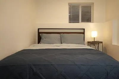 a bedroom with a bed with a black comforter and a lamp at Private Suite Steps to Main St. in Vancouver