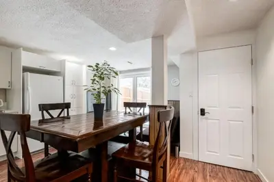 a kitchen and dining room with a wooden table and chairs at Simplistic 2BR Suite near Nose Hill & Airport in Calgary