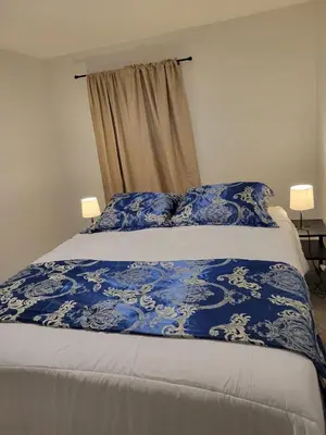 a bed with a blue and white blanket on it at Private Family Hideaway or Business Travel in Edmonton - 2 Bedroom Apartment in Edmonton