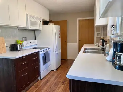 a kitchen with a white refrigerator and a sink at Mountain View Executive Suite in Grande Cache