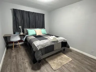 a bedroom with a bed with a desk and a chair at Cute Highland Park Entire Unit A in Calgary