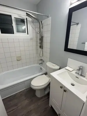 a white bathroom with a toilet and a sink at Cute Highland Park Entire Unit A in Calgary