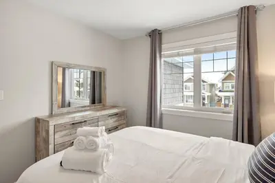 a bedroom with a bed with a mirror and a window at Luxurious Entire House with Cental AC, Double Car Garage Parking, Upgraded Appliances, King Size Bed, Two Living Rooms & More in Nisku