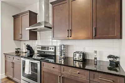 a kitchen with wooden cabinets and a stove top oven at Luxurious Entire House with Cental AC, Double Car Garage Parking, Upgraded Appliances, King Size Bed, Two Living Rooms & More in Nisku