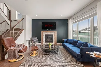 a living room with a blue couch and a fireplace at Luxurious Entire House with Cental AC, Double Car Garage Parking, Upgraded Appliances, King Size Bed, Two Living Rooms & More in Nisku