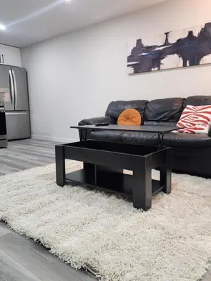 a black couch sitting on a rug in a living room at Trendy 2-Bed Oasis Awaits! in Calgary