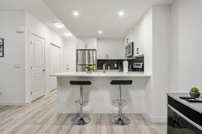 a kitchen with white cabinets and bar stools at Angie’s place in Calgary