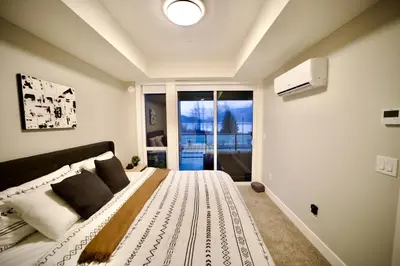 a bedroom with a large bed with a large window at Dreamy Panoramic Lakeview 1 Bedroom plus Den in Harrison Hot Springs