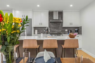 a kitchen with white cabinets and a table with chairs at Brand New - TimberLodge Spacious 2br in Canmore