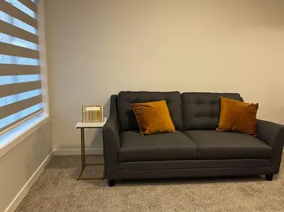 a black couch with two orange pillows in a room at Brand New - Home Away from Home in NW Calgary in Calgary