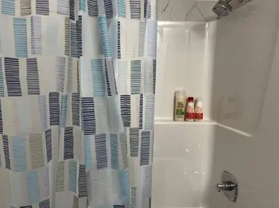 a bathroom with a shower curtain full of books at Brand New - Home Away from Home in NW Calgary in Calgary