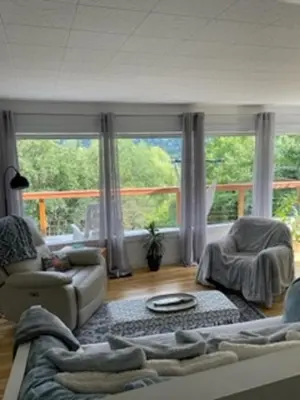 a living room with a couch and a large window at Sweet Creek Retreat in Nelson
