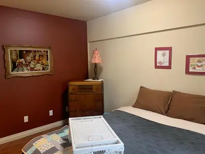 a bedroom with a bed and a dresser with a lamp at Shoreside Private room in Sechelt