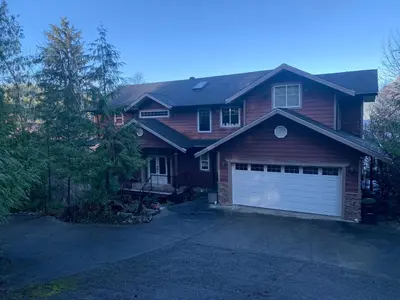 a brown house with a garage with a driveway at Shoreside Private room in Sechelt