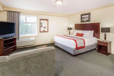 a hotel room with a bed and a flat screen tv at Ramada by Wyndham Hinton in Hinton