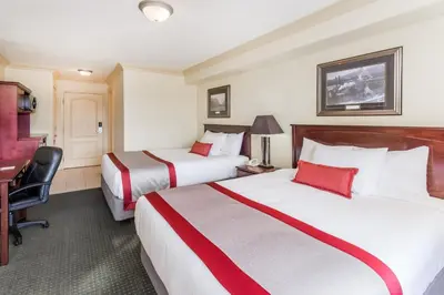a hotel room with two beds and a desk at Ramada by Wyndham Hinton in Hinton