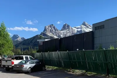 a car parked next to a fence with mountains in the background at The Mountain Loft in Canmore