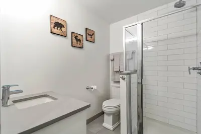 a white bathroom with a toilet and a sink at Mountain Modern Hideaway in Canmore