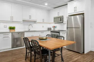 a kitchen with a wooden table and a stainless steel refrigerator at Mountain Modern Hideaway in Canmore