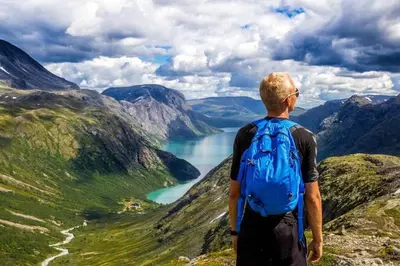 a man with a backpack standing on top of a mountain at Mountain Modern Hideaway in Canmore