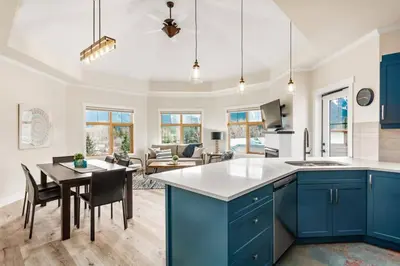 a kitchen and living room with blue cabinets and a table at The Grand Escape Downtown Canmore in Canmore