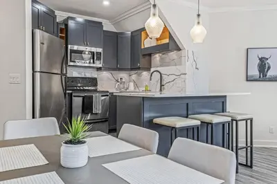 a kitchen with black cabinets and a table and chairs at Mountain Vista Escape Downtown in Canmore