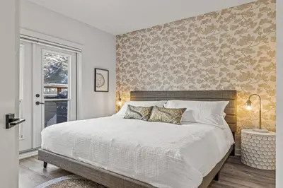 a bedroom with a large white bed with a wall at Mountain Vista Escape Downtown in Canmore