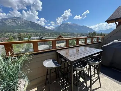 a wooden table and chairs on a balcony with mountains at Mountain Vista Escape Downtown in Canmore