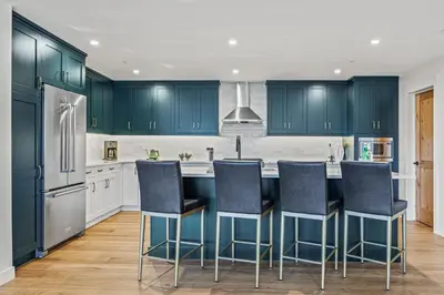 a kitchen with blue cabinets and a kitchen island with bar stools at Serenity Villa at Tamarack in Canmore