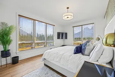 a bedroom with a large bed and two windows at Serenity Villa at Tamarack in Canmore