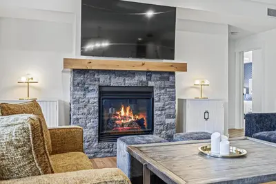 a living room with a fireplace and a table at Serenity Villa at Tamarack in Canmore
