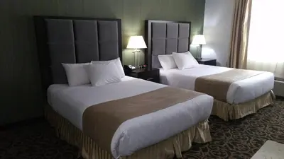 a hotel room with two beds and two lamps at Paradise Inn and Suites Redwater in Redwater